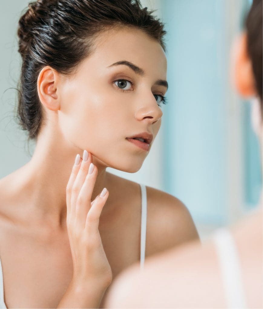 Young woman looking at her skin in the mirror